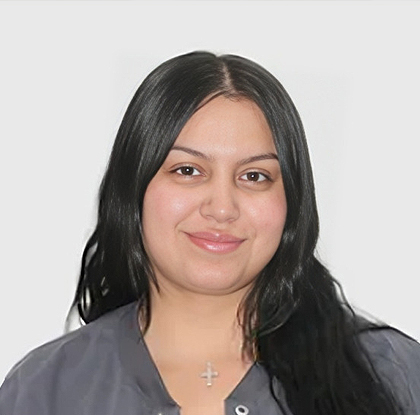 Young woman with long dark hair wearing cross necklace, professional headshot against white background.