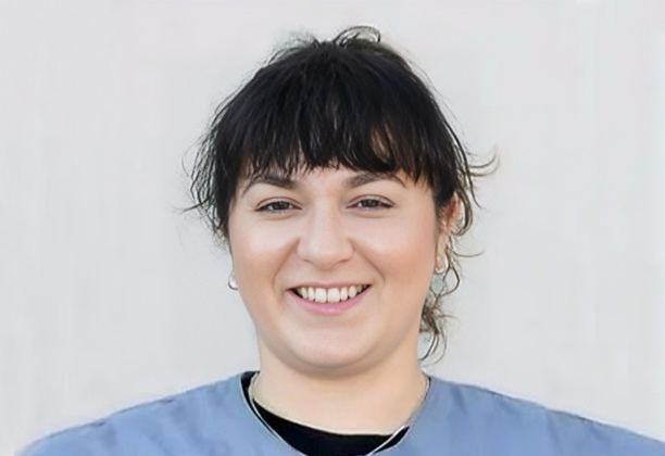 Smiling woman wearing blue shirt against white background, professional headshot photo.