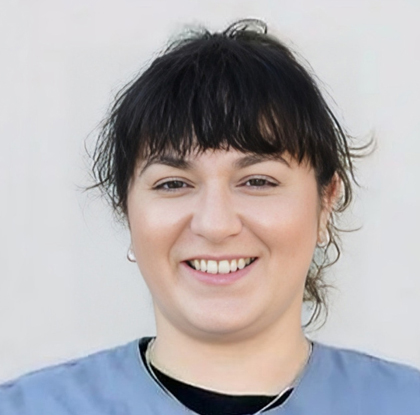 Smiling woman with black bangs wearing blue shirt in professional headshot.