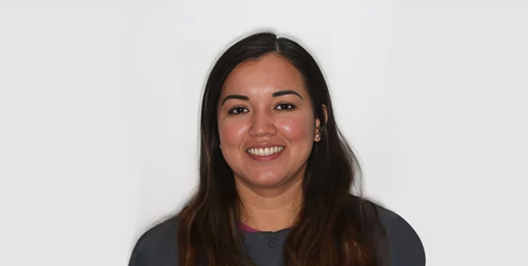 Professional headshot of a smiling woman with long dark hair against a white background.