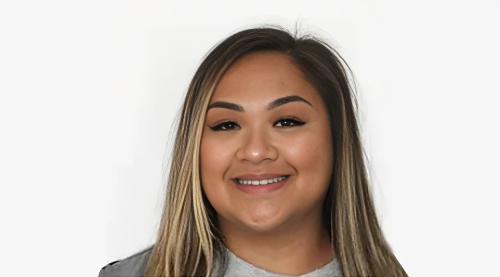 Woman smiling at camera against white background, professional headshot for dental practice.