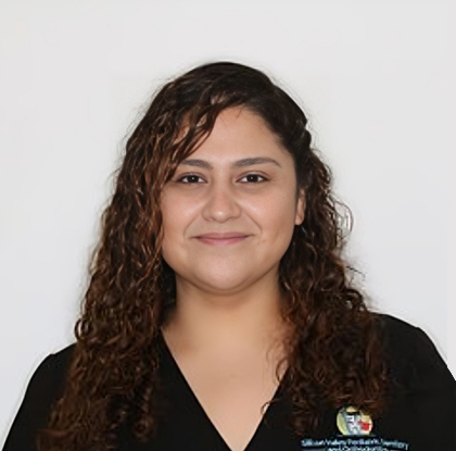 Professional headshot of female dental staff member wearing black scrubs against white background.