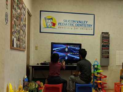 Children watching animated movie in Silicon Valley Pediatric Dentistry waiting room with toys.