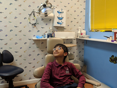 Young patient sitting in dental chair at pediatric dentistry office during examination.