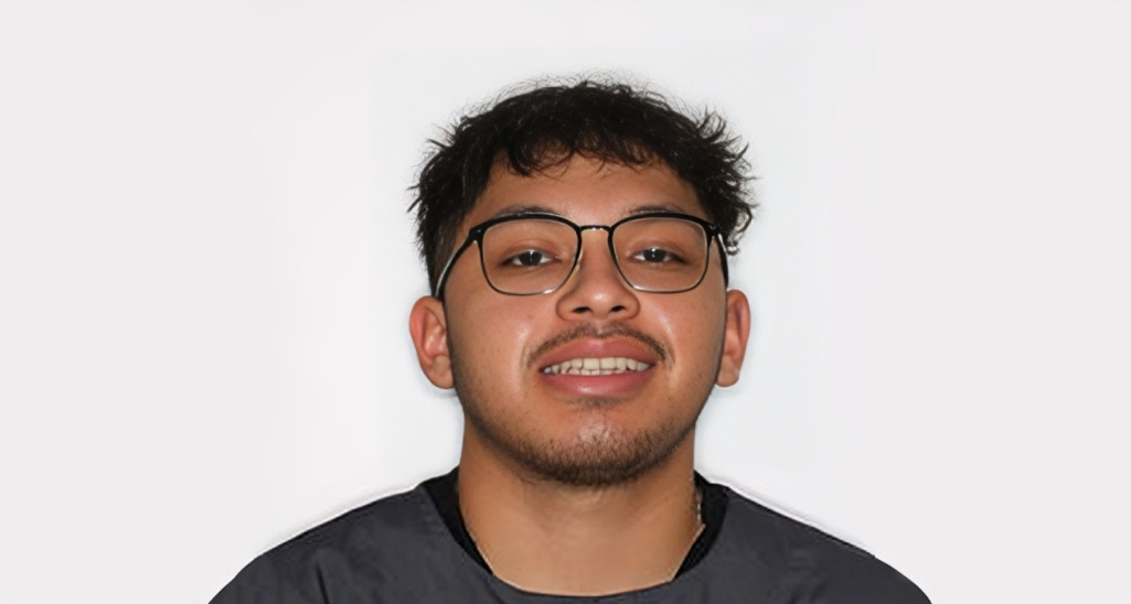 Young man wearing glasses and black shirt smiling at camera against white background