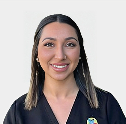 Professional headshot of female dental staff member smiling at camera wearing dark scrubs.