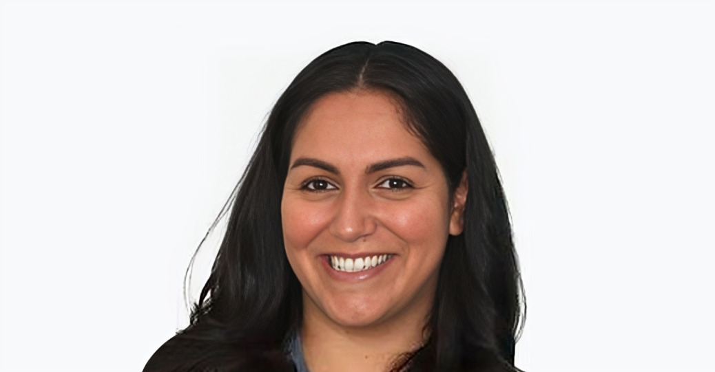 Professional headshot of a smiling woman with long dark hair against a white background.