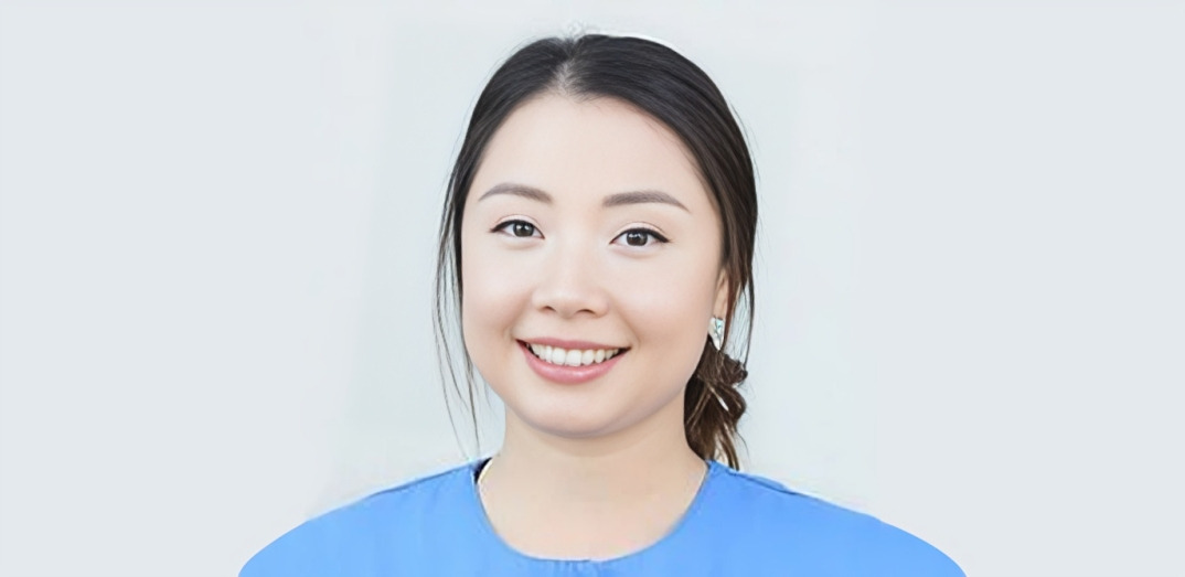 Smiling woman in blue shirt against white background, professional headshot for dental practice.