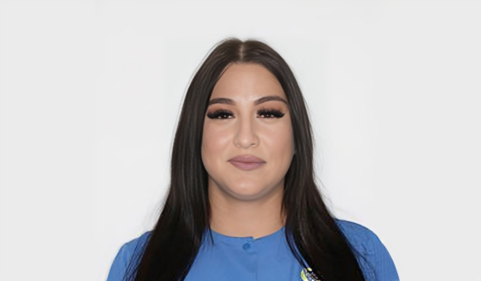 Woman with long dark hair wearing blue shirt against white background, professional headshot.