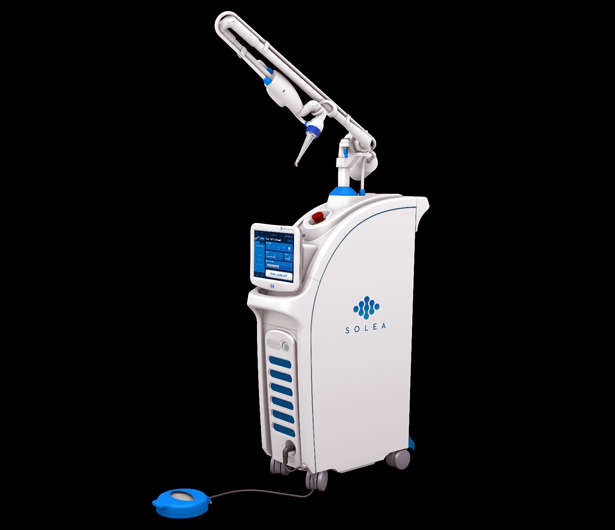 Professional dental laser equipment with articulated arm and control panel in clinical setting.