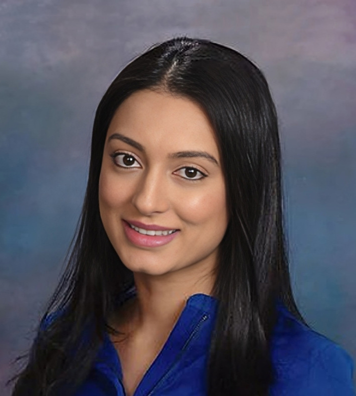 Professional headshot of woman with long black hair wearing blue top against blue gradient background.