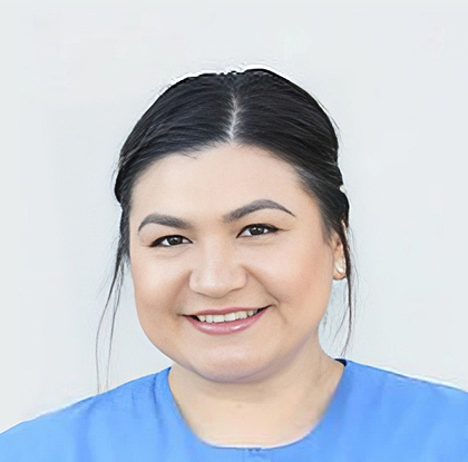 Woman in blue scrubs smiling at camera, professional headshot for dental practice.