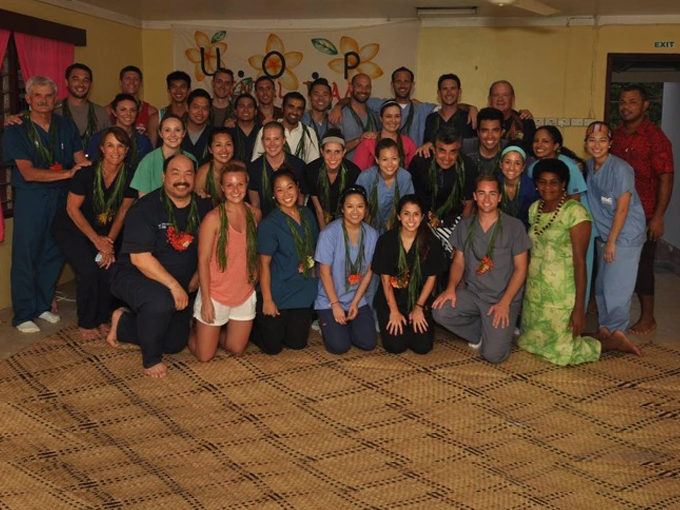 Large group of dental staff and team members posing together in an indoor clinic setting.