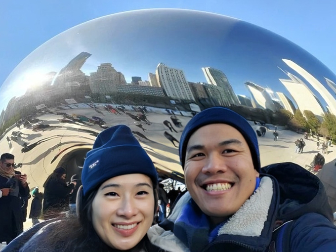 Two people smiling at famous Bean sculpture in Chicago during winter visit.