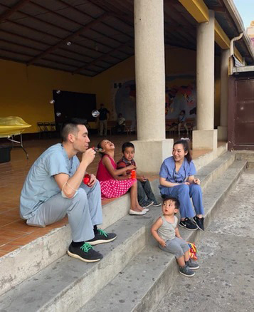 Pediatric dentist engaging with children in outdoor educational setting at dental practice.