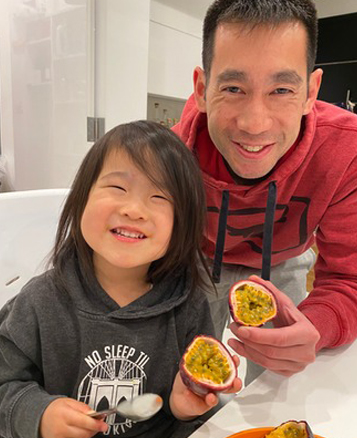 Adult and child smiling while holding passion fruits in a bright dental office setting.