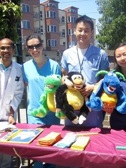 Team members displaying colorful puppet characters at outdoor community event table.