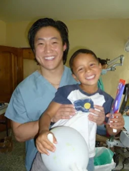 Two people holding a stuffed animal toy in a home interior setting, smiling at camera.