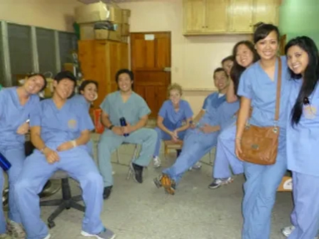Pediatric dental staff in scrubs gather together in clinic hallway for team photo.