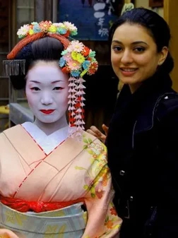 Woman posing next to geisha doll display in dental office setting.