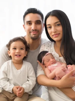 Happy family with two children and newborn baby posing together indoors.