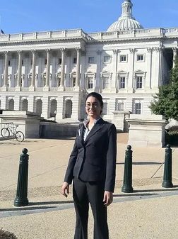 Professional woman in business attire standing in front of U.S. Capitol Building.