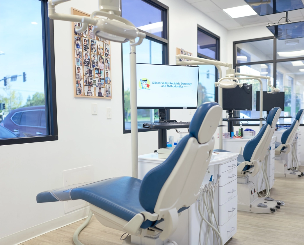 Modern pediatric dental operatory with blue patient chair and clinical equipment in bright office.