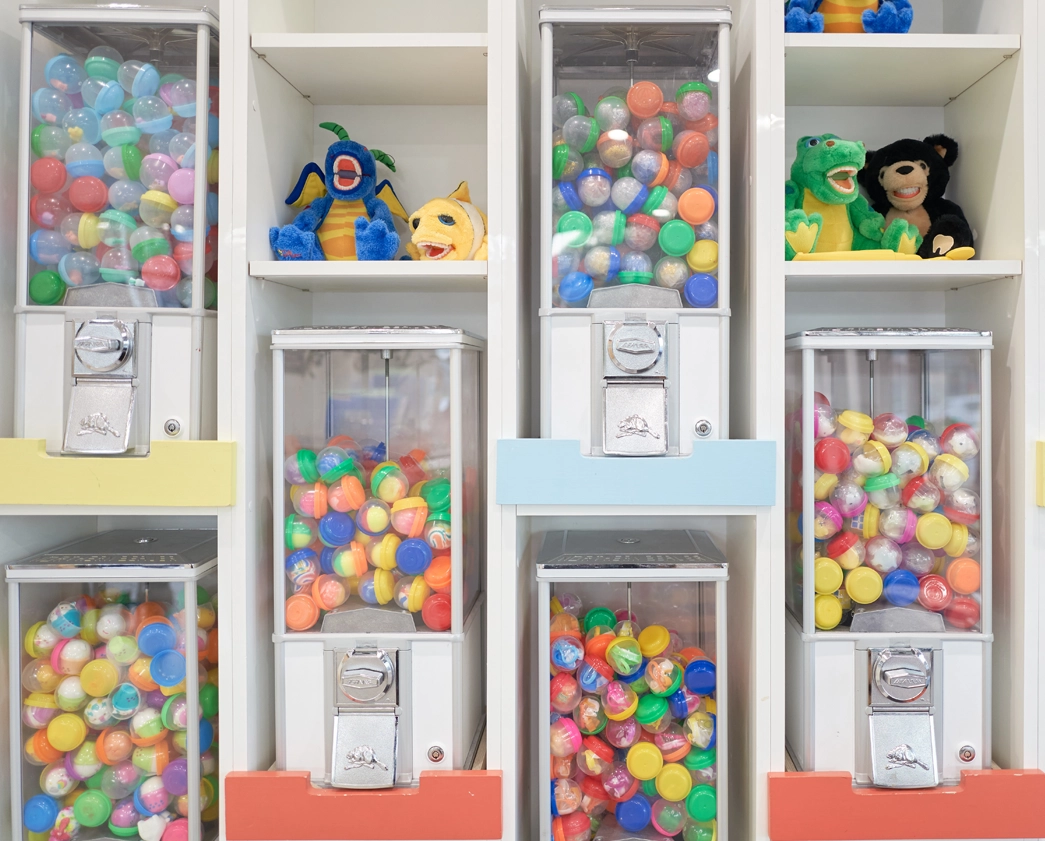 Colorful gumball machines filled with bright spheres displayed on white shelving unit in pediatric dental office.