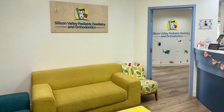 Bright waiting room with yellow couch and teal accents at pediatric dental office.