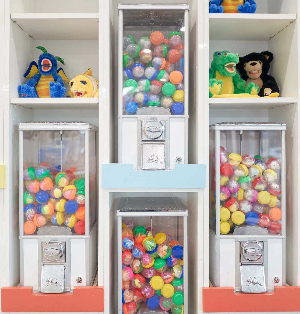 Wall of gumball machines and toy dispensers in pediatric dental office waiting room.