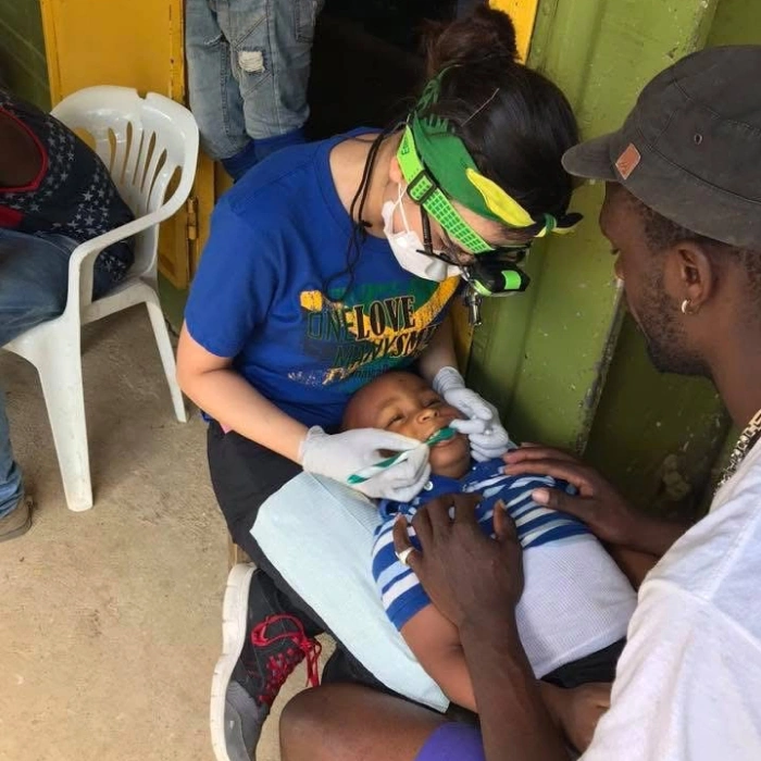 Pediatric dentist examines young patient's teeth during dental checkup in clinical setting.