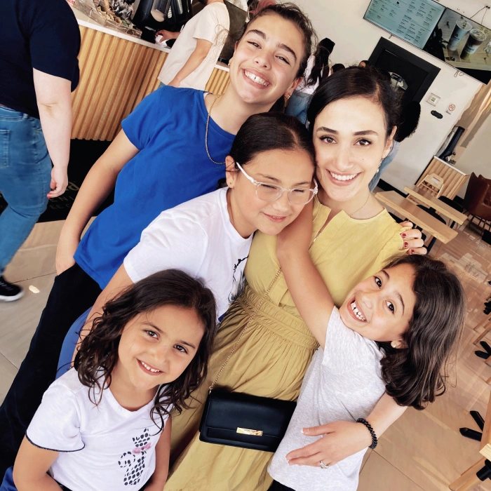 Family of five smiling together indoors at dental office, showing happy patients and staff.