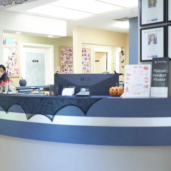 Pediatric dental office reception desk with staff member and bat decorations for Halloween.