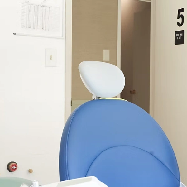 Pediatric dental chair in modern office operatory with overhead light and treatment room entrance.