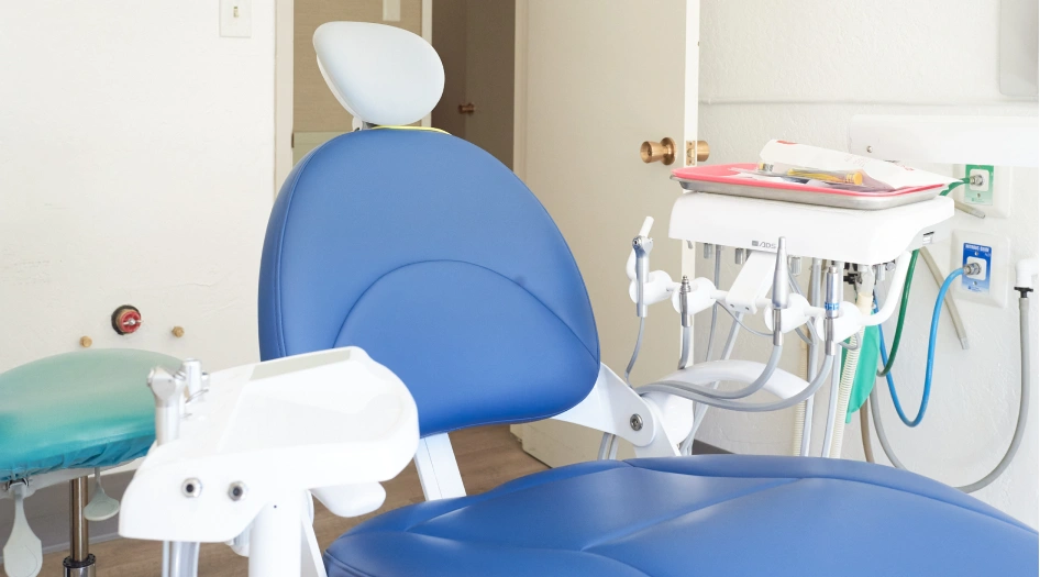 Pediatric dental operatory with blue chair, overhead light, and sterilized instruments ready for patient care.