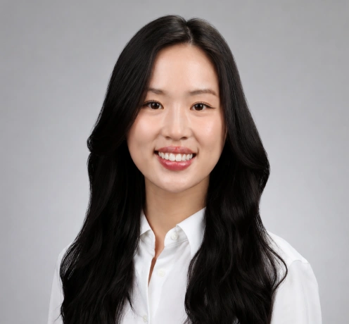 Professional headshot of Dr. Erinn Chang smiling with long dark hair, wearing a white collared shirt against a gray background.