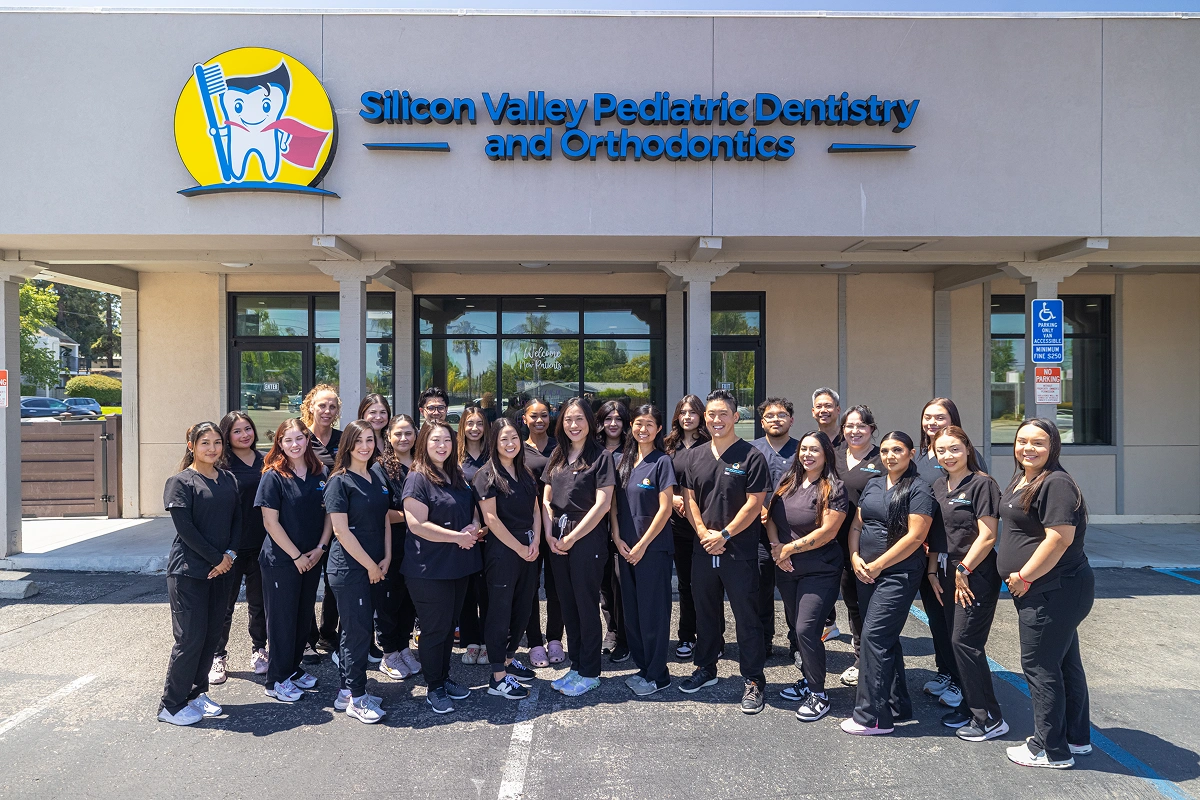 Large group photo of the entire dental team standing in uniform outside the entrance of Silicon Valley Pediatric Dentistry and Orthodontics.