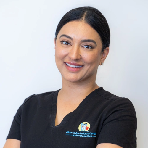 Professional headshot of Dr. Sona Gill smiling, wearing black scrubs against a white background.