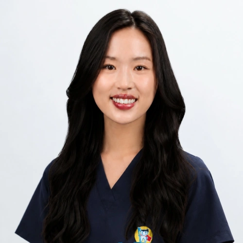 Headshot of Dr. Erinn Chang, a smiling woman with long, wavy black hair, wearing dark blue medical scrubs against a plain white background.
