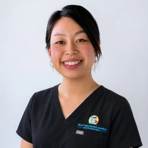 Headshot of Dr. Arden Hu, a smiling woman with her black hair tied back and wearing small earrings. She is wearing black medical scrubs with a "Silicon Valley Pediatric Dentistry and Orthodontics" logo, set against a light gray background.
