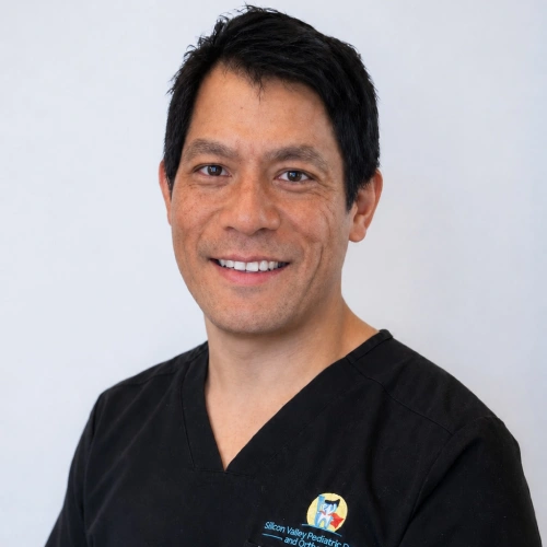 Headshot of Dr. James Ikehara, a smiling man with short black hair, wearing black medical scrubs with a partial logo visible on the left chest, set against a plain white background.